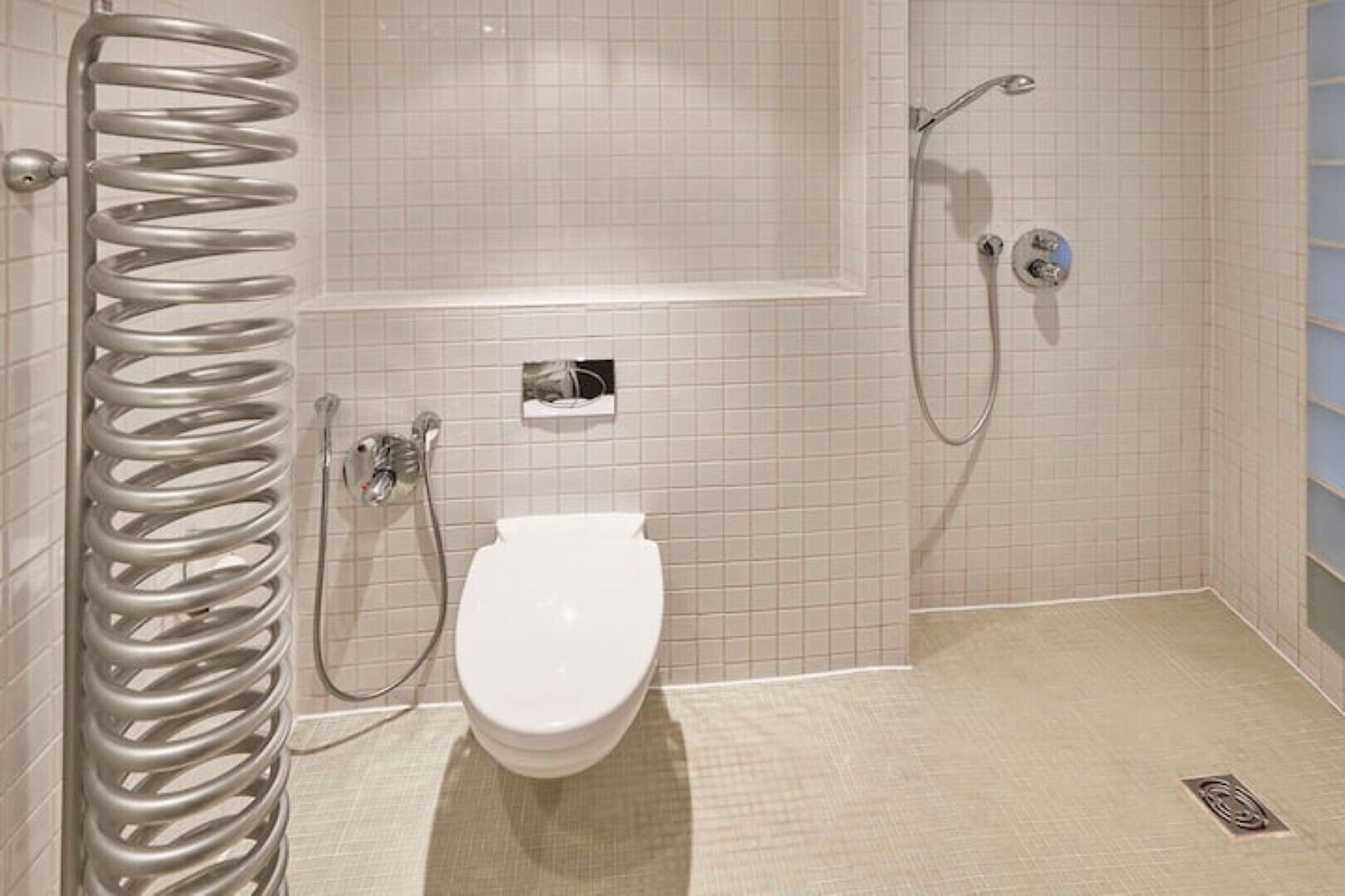 A modern bathroom with a toilet, a shower, and a metal spring.