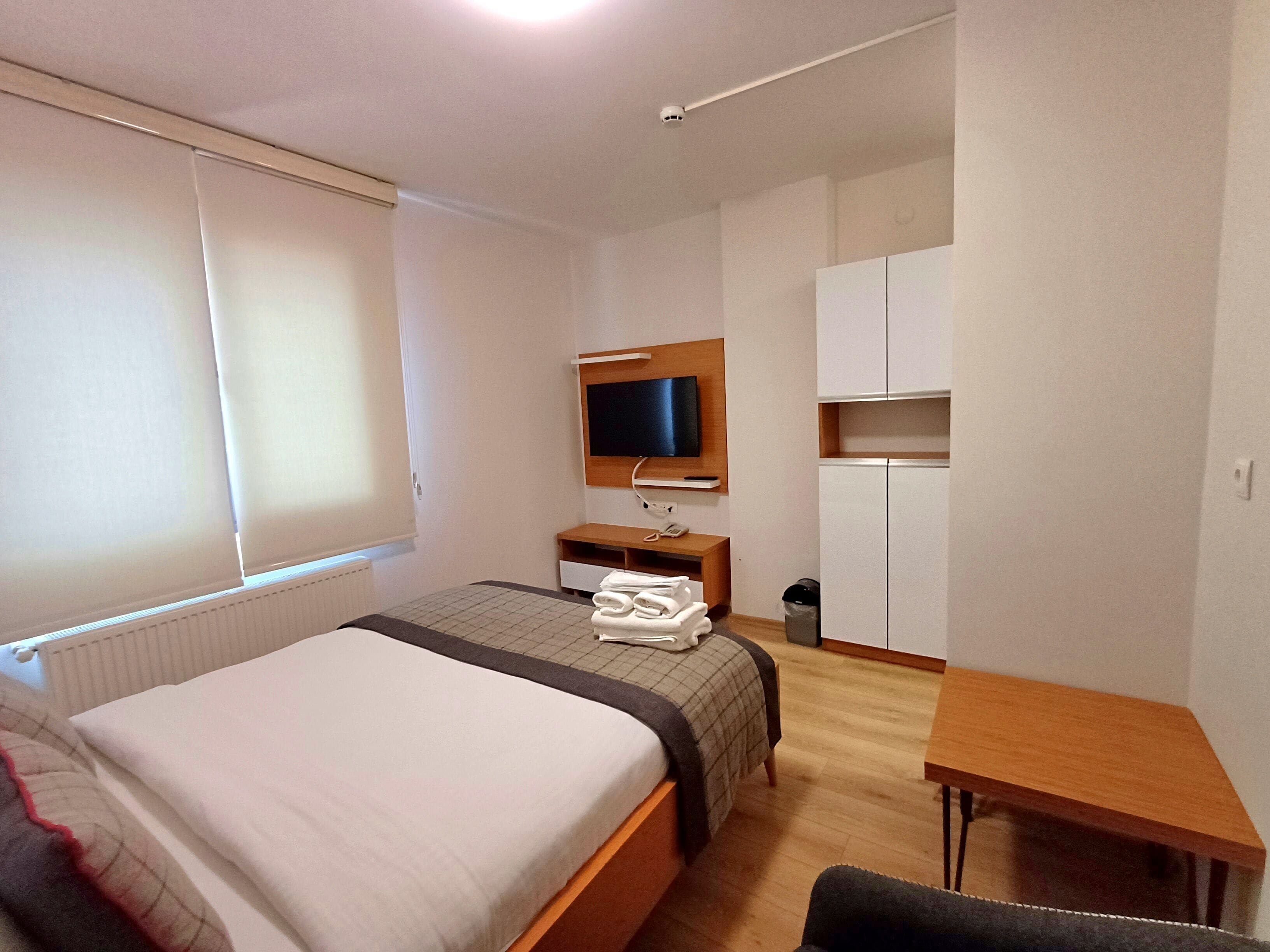 Ein Hotelzimmer mit Bett, Schreibtisch, Fernseher und Kleiderschrank.