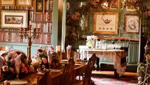 A dining area with a table set for four, surrounded by bookshelves filled with books. - Oak View Manor (Lesedi)