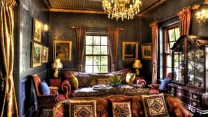 A room with a large window, a chandelier, and a piano. - Oak View Manor (Lesedi)