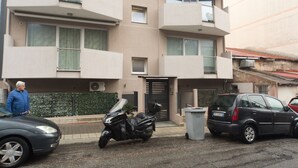 A multi-story residential building with balconies, a parked motorcycle, and a car in front. - Slow Chic Apartment b&b policlinico (Messina)