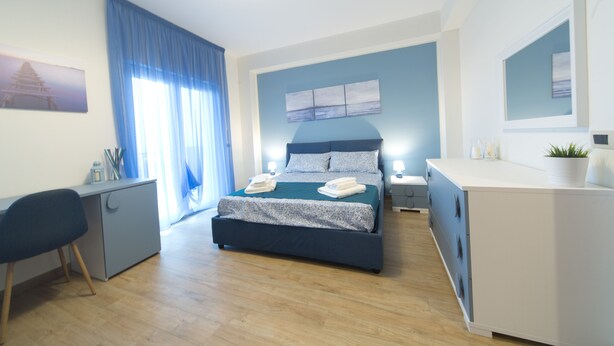 A modern bedroom with a bed, desk, and dresser. - Slow Chic Apartment b&b policlinico (Messina)