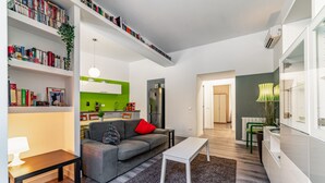 A modern living room with a grey sofa, a white coffee table, and a bookshelf filled with books. - Casa Fabrizio (Rome)