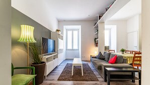 A modern living room with a TV, sofa, and coffee table. There is a potted plant and a lamp. - Casa Fabrizio (Rome)