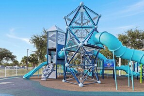 Un parque infantil con una estructura para escalar, toboganes y una casita, identificada como 'DESTIN FORT WALTON BEACH FLORIDA'.