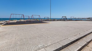 An empty playground with swings and a slide, a paved area, and a tall streetlight. - 3311 Bianca House by Barbarhouse (Squinzano)