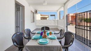 A balcony with a table set for dining, chairs, and a view of the street. - 3311 Bianca House by Barbarhouse (Squinzano)