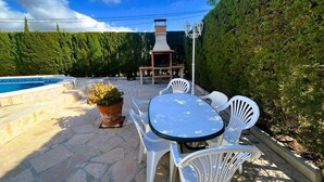 Une terrasse avec une piscine, des chaises blanches et une table.