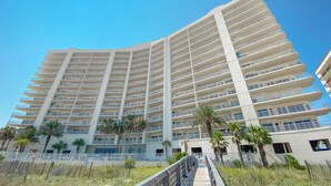 A multi-story hotel with a modern design, featuring balconies and a central walkway. - Admirals Quarters 1403-Beachfront | 2 King Suites | Free parking for 2 Vehicles (Orange Beach)
