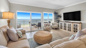 A living room with a sofa, ottoman, and a television. - Admirals Quarters 1403-Beachfront | 2 King Suites | Free parking for 2 Vehicles (Orange Beach)