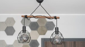 Un luminaire suspendu de style industriel, doté d’un design géométrique et d’une poutre en bois.