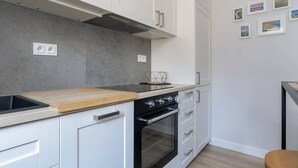 Une cuisine moderne avec des meubles blancs, un four noir et un plan de travail en bois.