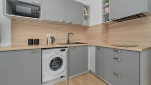 Une cuisine compacte avec des meubles gris, un lave-linge encastré, un four à micro-ondes et un évier.