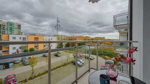 Un balcon donnant sur un parking et les bâtiments environnants.