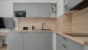 Une cuisine moderne avec des meubles gris, un plan de travail en bois, un four à micro-ondes encastré et une machine à café.