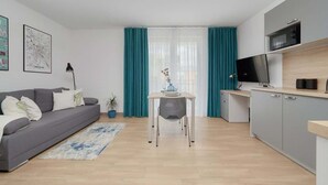 Un appartement moderne avec un canapé gris, une table à manger et un coin cuisine.