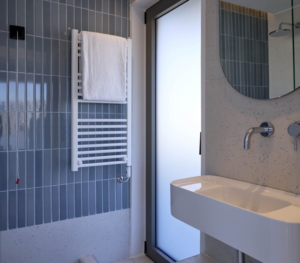 A bathroom with a white sink, a mirror, and a towel rack.