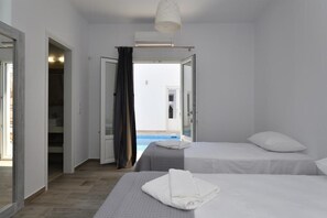 A hotel room with two beds, a shower, and a view of a swimming pool. - Nisides Villas Naoussa (Naousa)