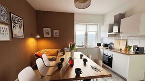 Una cucina moderna con mobili bianchi, un tavolo da pranzo in legno e vista sulla città attraverso la finestra.