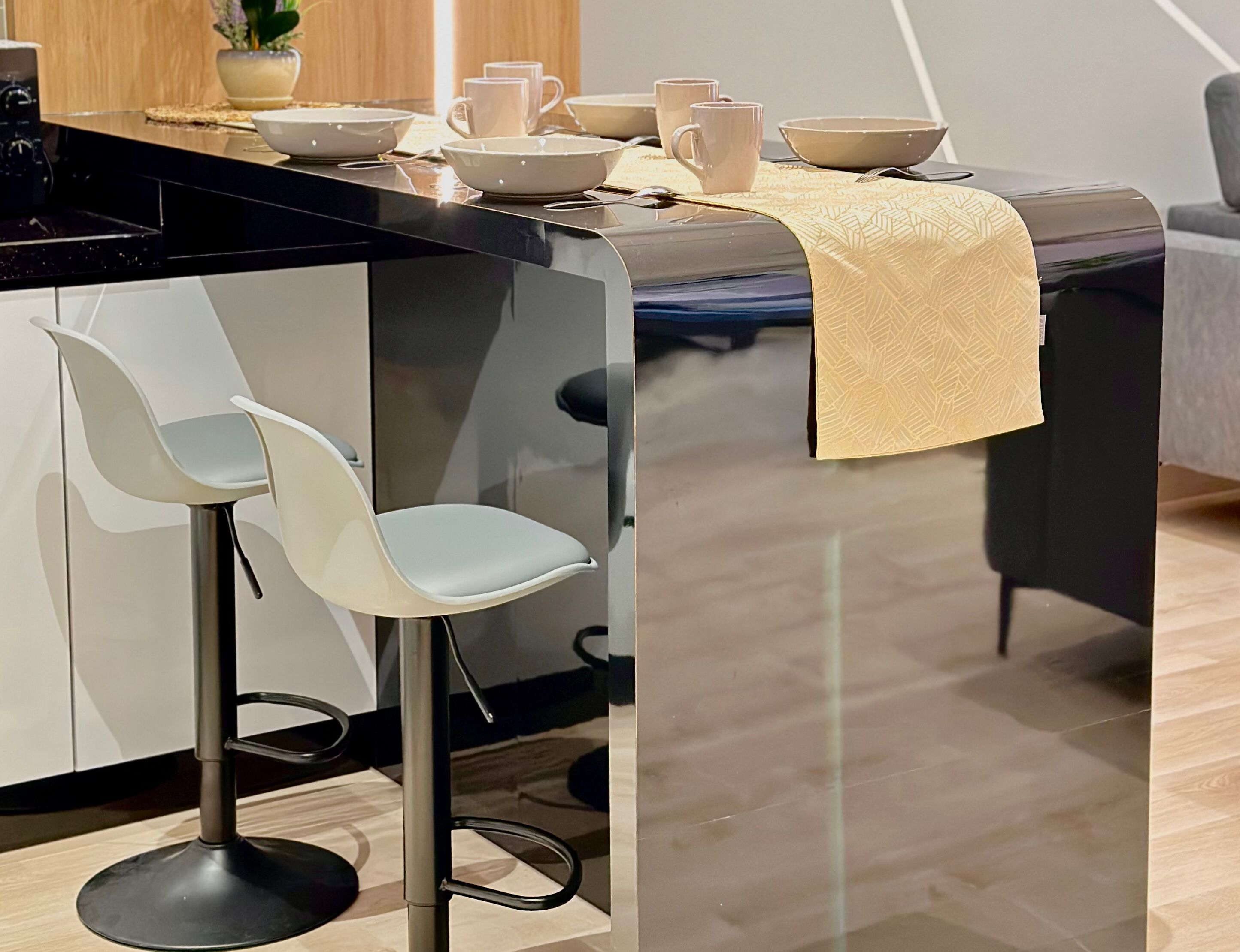Eine moderne Küche mit schwarzem Arbeitsplatz, weißen Barhocker und einem Essbereich mit Tisch für vier Personen.