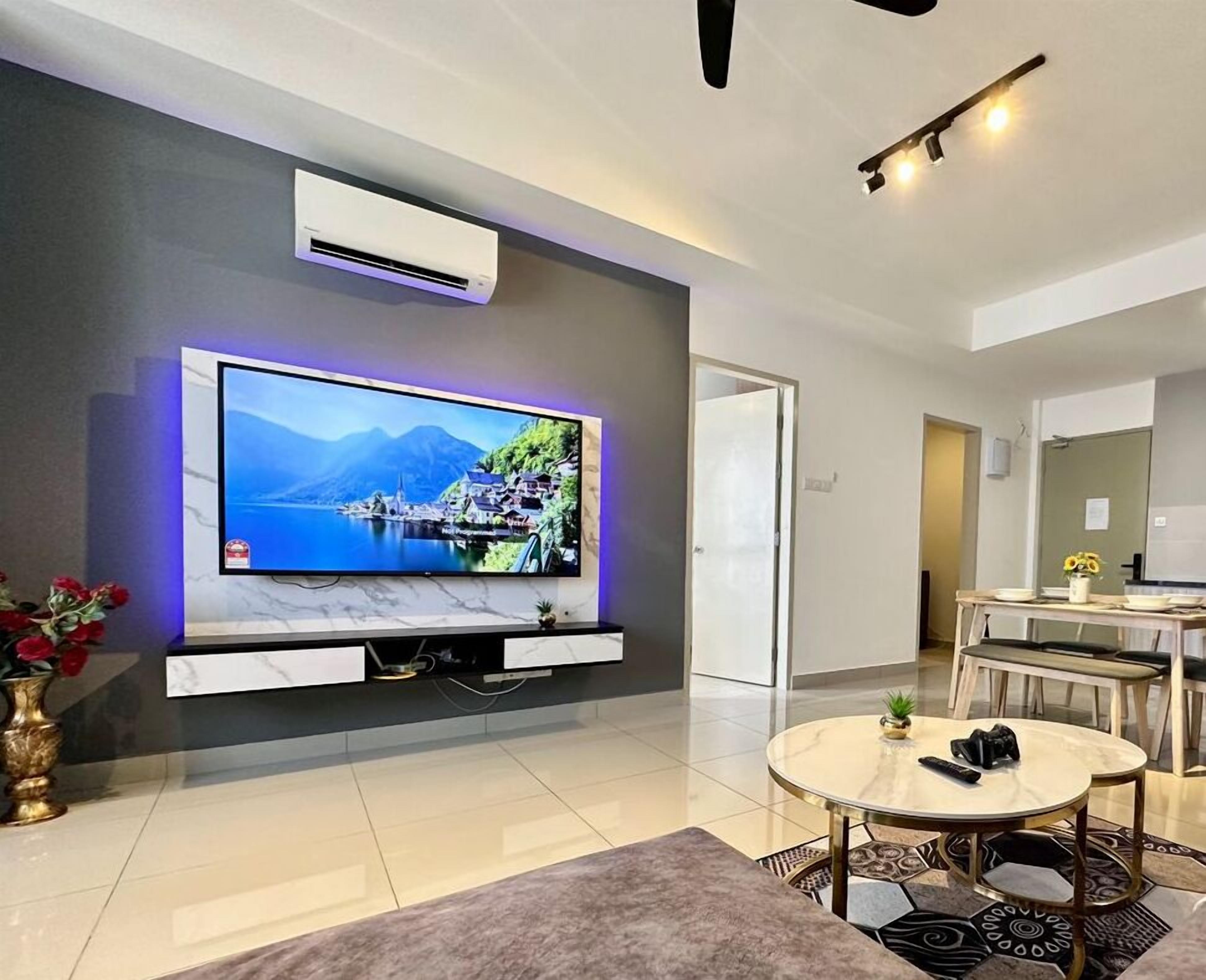 Een moderne woonkamer met een flatscreen televisie bevestigd aan een marmeren muur, een eethoek met een tafel en stoelen, en een airconditioningsunit op het plafond.