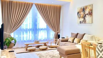 A modern living room with a sofa, ottoman, and a dining area with a table and chairs.