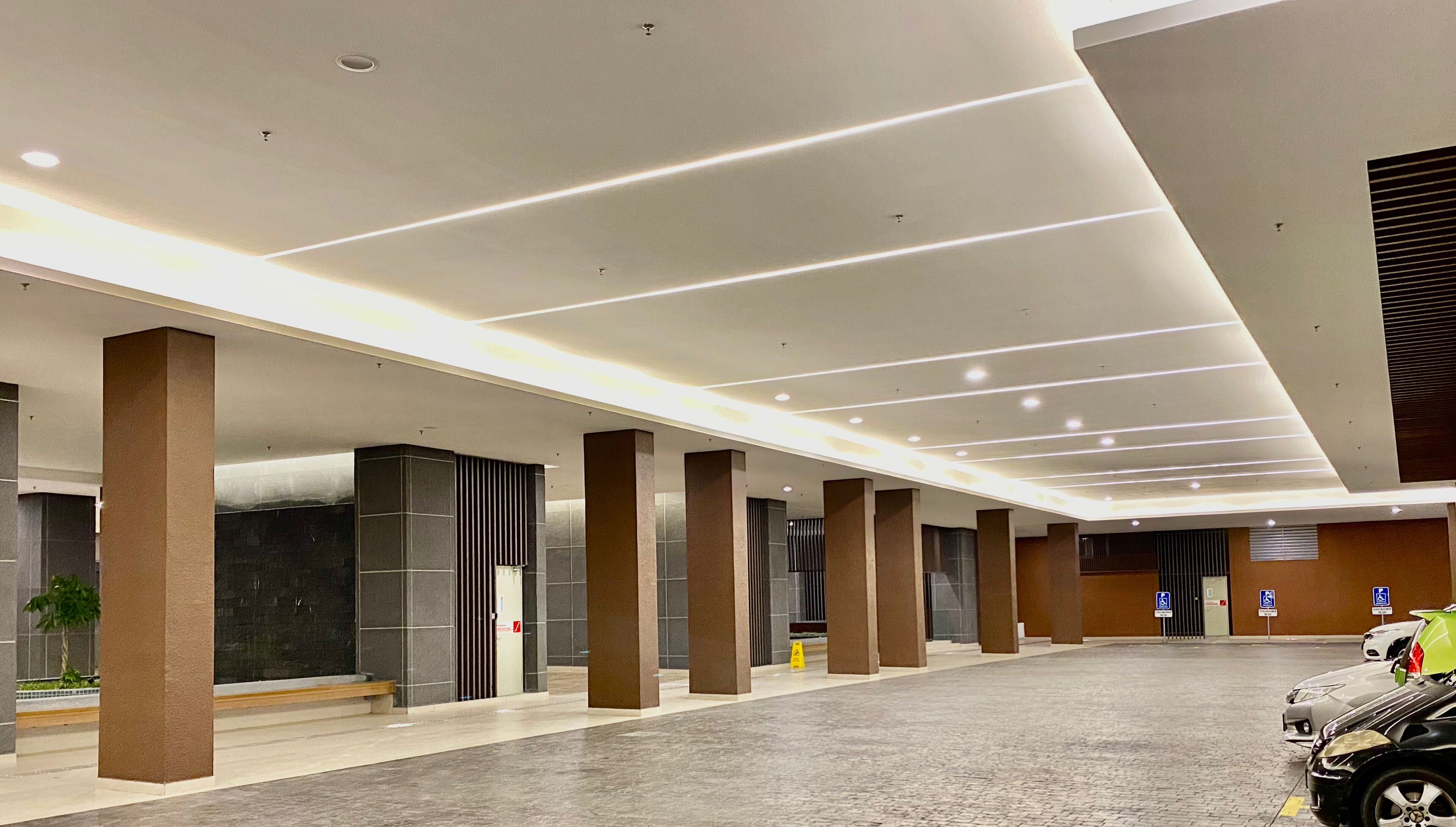 A spacious indoor area with a modern design, featuring a series of columns, a tiled floor, and a large open space.
