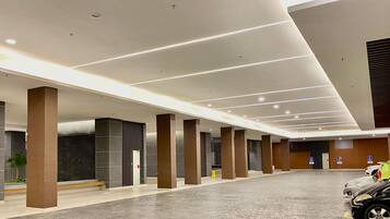 A spacious indoor area with a modern design, featuring a series of columns, a tiled floor, and a large open space.