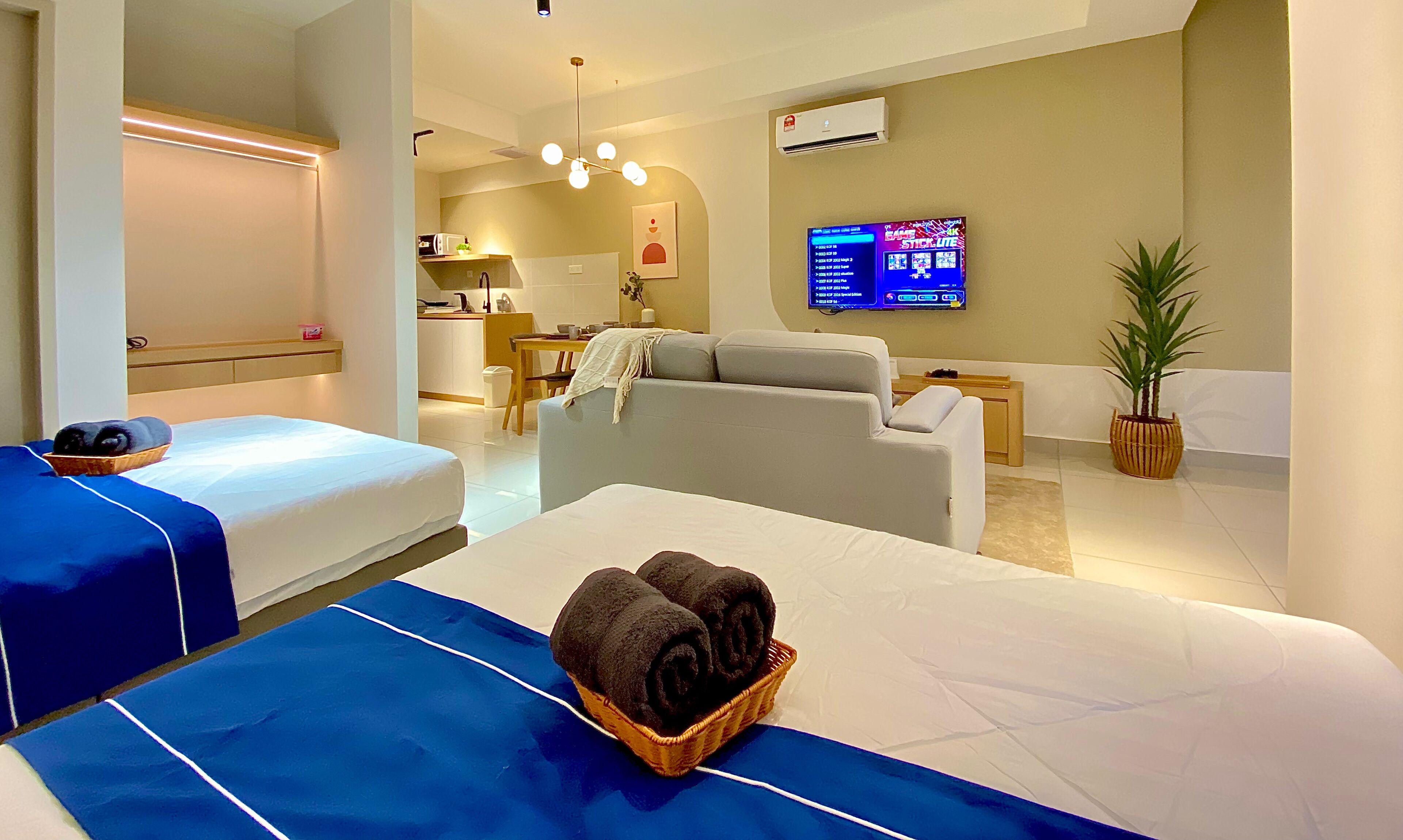 Een hotelkamer met twee bedden, een bank, een televisie en een kitchenette.