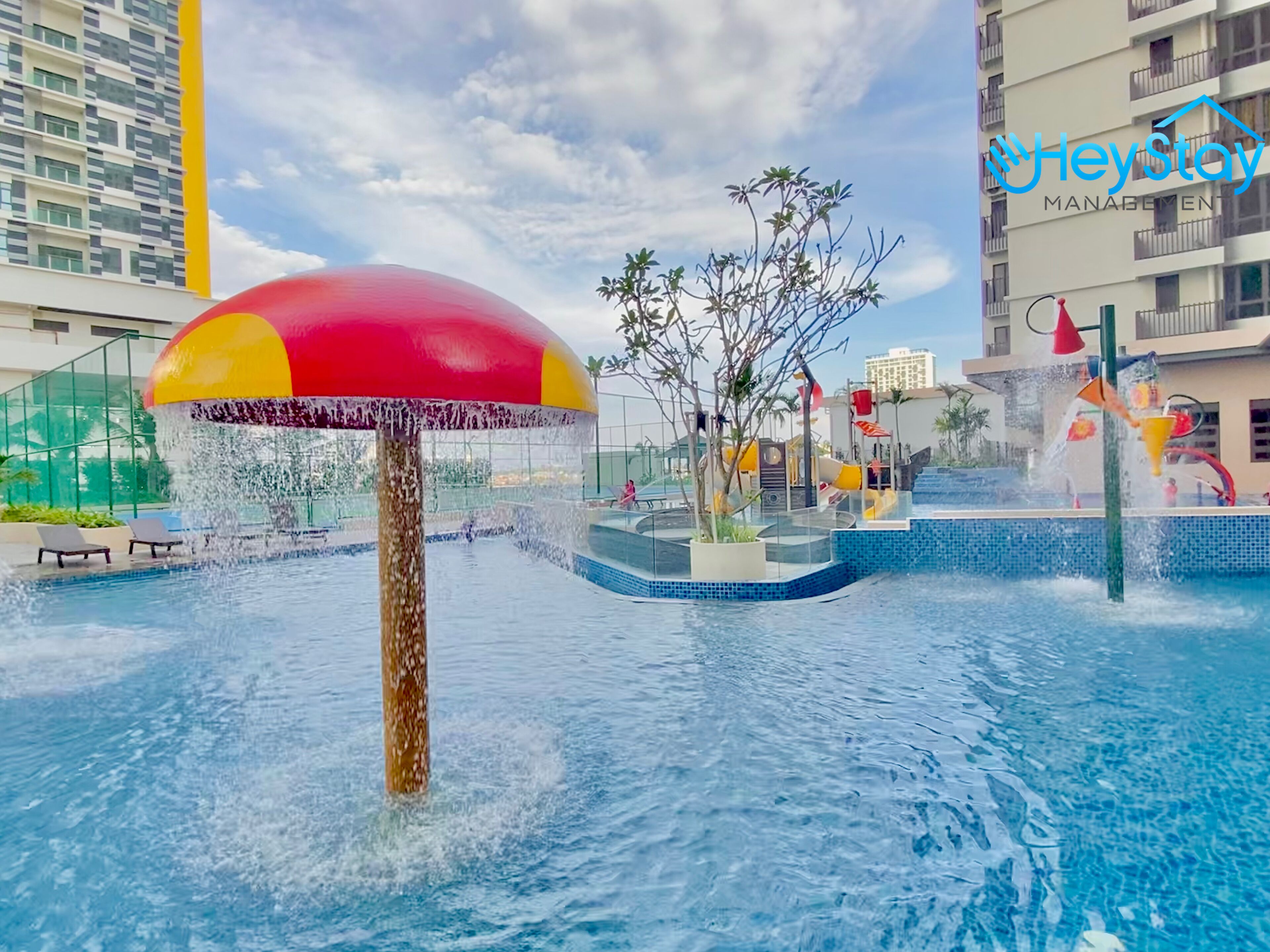 A water feature with a large umbrella, a pool, and a building in the background.