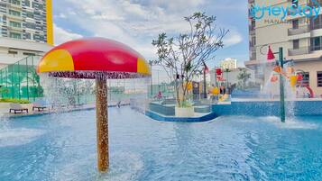 A water feature with a large umbrella, a pool, and a building in the background.
