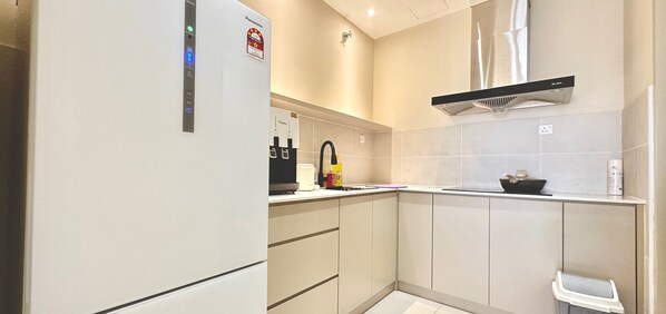 A modern kitchen with a built-in refrigerator, a coffee maker, and a microwave. - Bali Residence (Malacca City)
