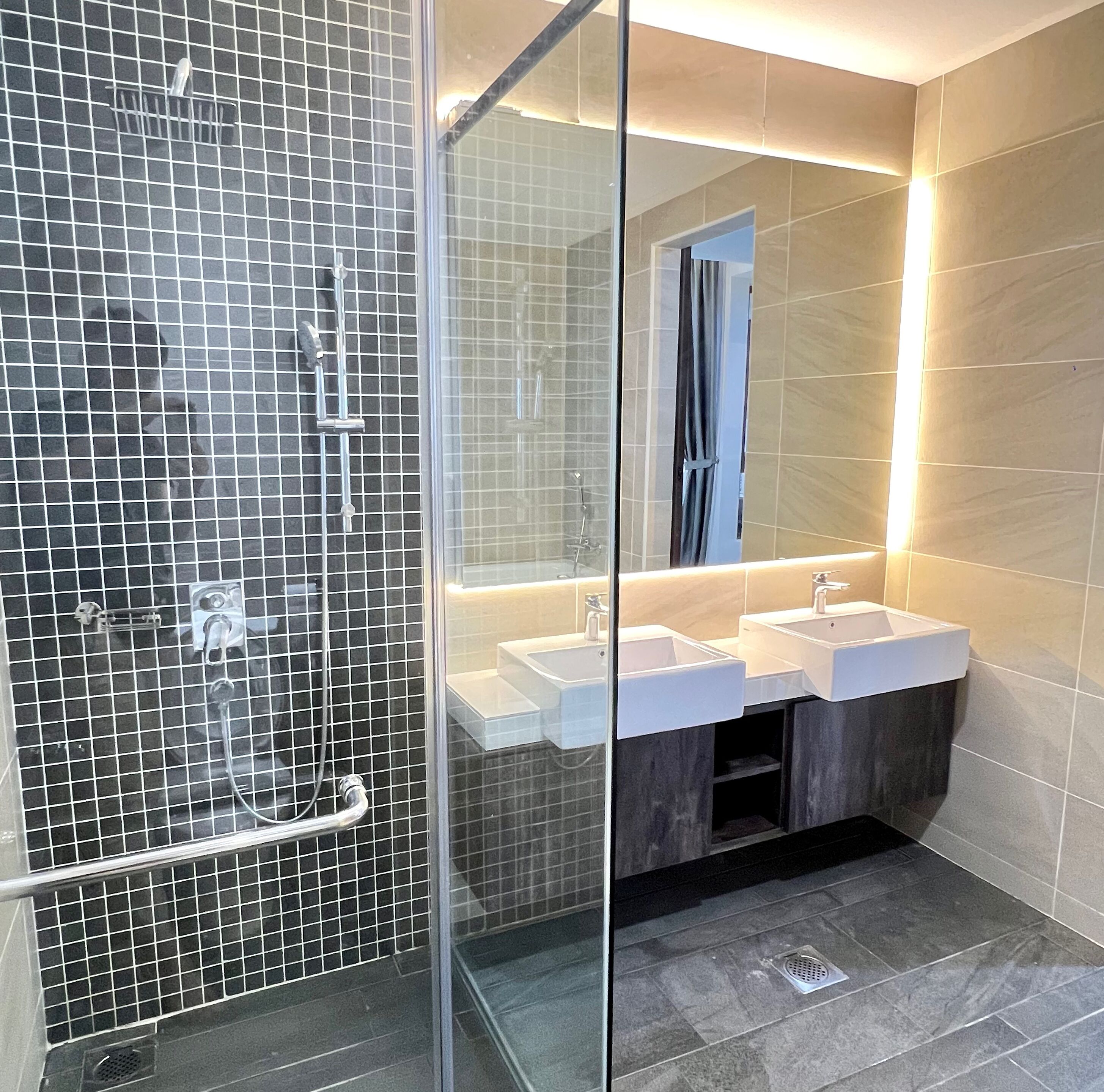 Un bagno moderno con doccia vetrata, due lavabi e uno specchio grande.