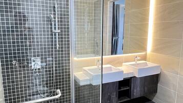 Un bagno moderno con doccia vetrata, due lavabi e uno specchio grande.