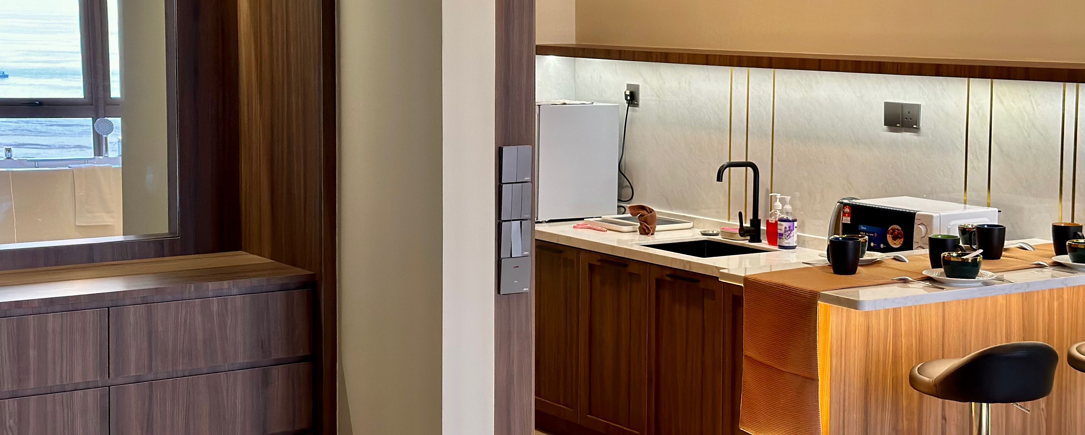 A modern kitchen with wooden cabinets, a stainless steel sink, and a window overlooking a body of water.