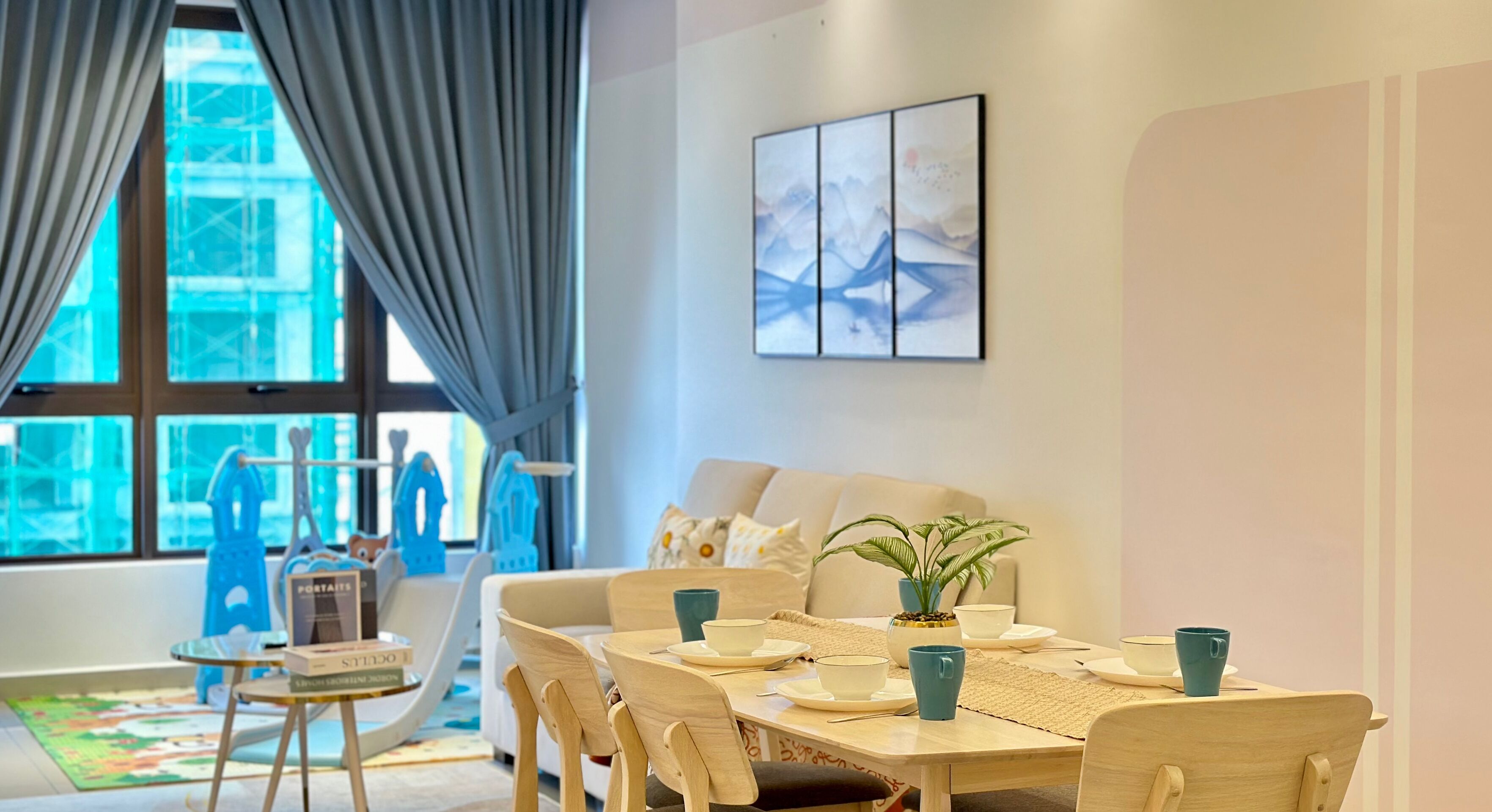 A dining area with a table set for four, a sofa, and a window with curtains.