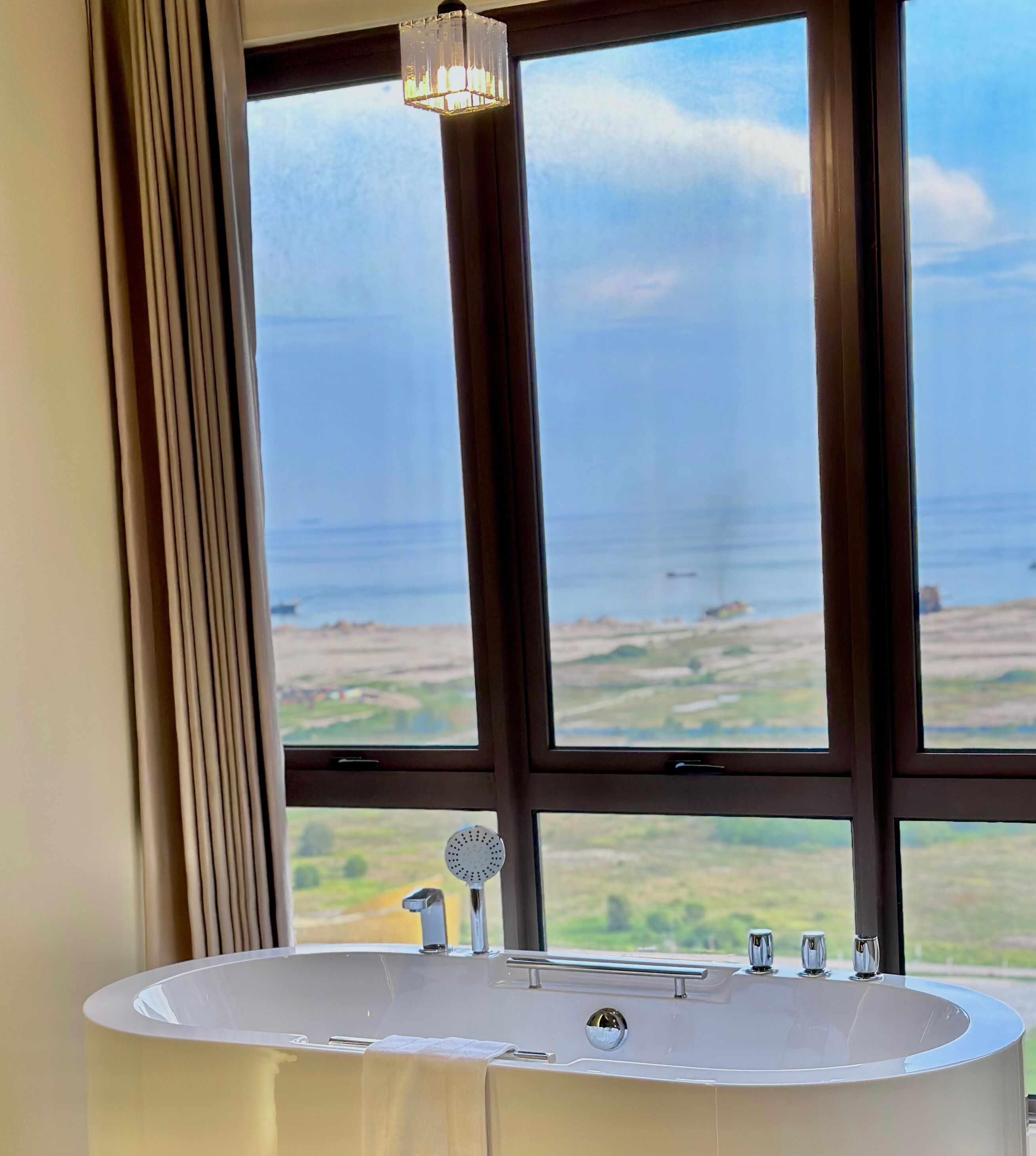 A bathroom with a large window, a bathtub, and a shower.