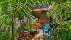 Un giardino tropicale con una pergola in legno, un tavolino e due sedie.