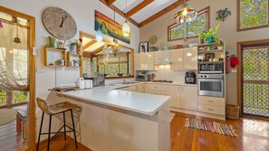 Una cocina moderna con una isla grande, piso de madera y vista a zonas verdes.