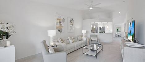 A modern living room with a sofa, armchairs, a coffee table, and a TV.