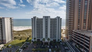 Un hôtel de grande hauteur avec une entrée principale, de nombreux balcons et une vue sur la plage.