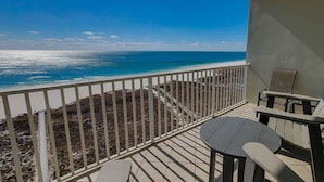 Un balcon avec vue sur l’océan, une table et deux chaises.