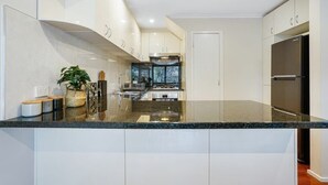 Una cocina moderna con una isla central, electrodomésticos de acero inoxidable y armarios blancos.