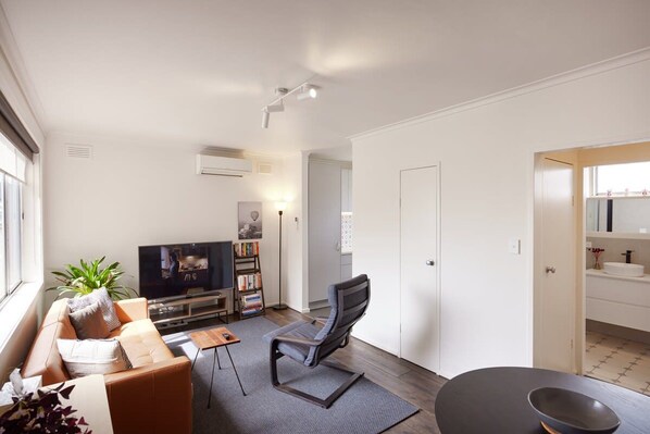 A modern living room with a sofa, TV, bookshelf, and a chair.