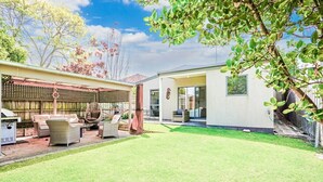 A backyard with a lawn, outdoor furniture, and a pergola.