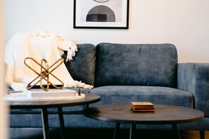 Un salon moderne avec un canapé gris, une table basse ronde et un tableau encadré accroché au mur.