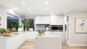 Una cocina moderna con armarios blancos, una isla central y un ventanal que ofrece vistas al exterior.