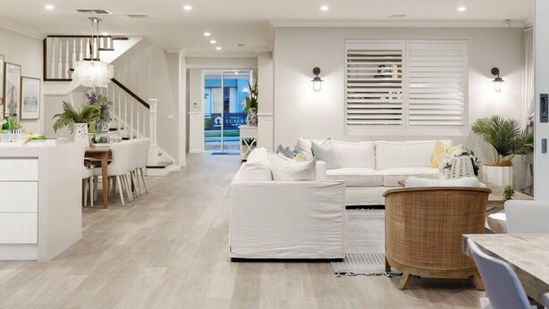 Una sala de estar moderna con un sofá blanco, una mesa de centro de mimbre y un comedor con una mesa y sillas blancas.
