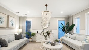 Una sala de estar moderna con un sofá blanco, una mesa de centro redonda y una araña.
