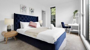 Une chambre moderne avec un grand lit, des tables de chevet, un bureau et une chaise.